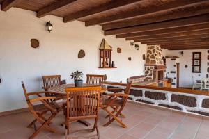 een eetkamer met een tafel en stoelen en een open haard bij Casa Tilama in Tinajo