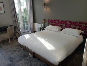 een slaapkamer met een groot wit bed met een rood hoofdeinde bij Chateau De Fere in Fère-en-Tardenois