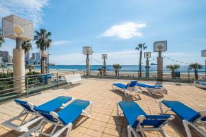 - une terrasse avec des chaises bleues et des chaises de plage dans l'établissement Santa Margarita Deluxe 14-B Levante Beach, à Benidorm