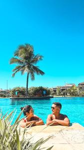 dwoje ludzi leżących w wodzie przy basenie w obiekcie Golf Ville Resort Brisa do Golf -Apartamentos e Cobertura w mieście Aquiraz