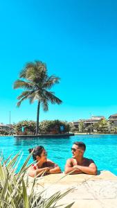 two people laying in the water at a pool at Golf Ville Resort Brisa do Golf -Apartamentos e Cobertura in Aquiraz