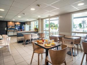 uma sala de jantar com mesas e cadeiras num restaurante em B&B HOTEL Cholet Nord em Cholet