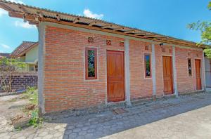 una casa de ladrillo con puertas rojas en una calle en OYO Life 93010 Omah Bareng Syariah Sambisari, en Kalasan