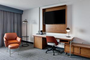 a hotel room with a desk and a tv and chairs at Courtyard by Marriott Detroit Downtown in Detroit