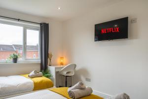 isimi Luxurious House Newcastle : غرفة نوم بسريرين وتلفزيون على الحائط