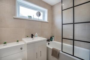 baño con lavabo, bañera y ventana en isimi Luxurious House Newcastle 