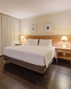 a large bed in a hotel room with two tables at King room - Brooklin flat in São Paulo