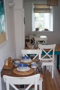una mesa de comedor con sillas blancas y platos azules y blancos en The Victoria, en Alderney