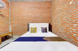 a brick walled room with a bed with two pillows at OYO Life 93010 Omah Bareng Syariah Sambisari in Kalasan
