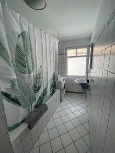 La salle de bains est pourvue d'un rideau de douche avec une plante. dans l'établissement Zentrale Altstadtkoje für bis zu 6 Personen, à Neustadt in Holstein