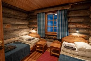a bedroom with two beds in a log cabin at Fell Centre Kiilopää, Hotelli Niilanpää in Saariselka
