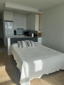 a large white bed in a room with a kitchen at Modern and Cozy apartment with Sauna2 in Espoo