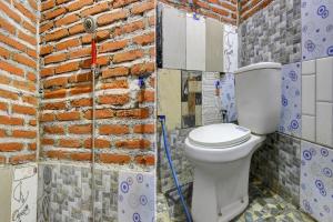 a bathroom with a toilet and a brick wall at OYO Life 93010 Omah Bareng Syariah Sambisari in Kalasan