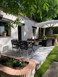 a patio with chairs and a table and an umbrella at Casa Rural 2 en un Fantástico Legado in Alfacar