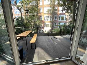 een balkon met een houten tafel en een bank bij Moderne dubbele benedenwoning met 3 slaapkamers in Rotterdam