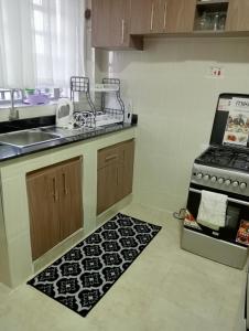 a kitchen with a stove and a sink and a rug at Amalya suites by TJ in Eldoret