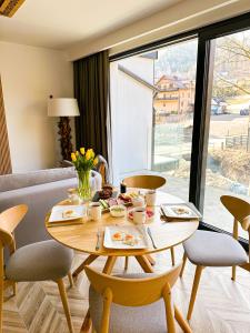 una mesa y sillas en una sala de estar con ventana en Kaskada Apartments & sauna na wyłączność, en Szczyrk