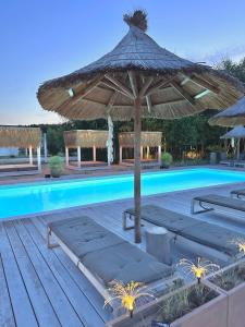 a pool with a large umbrella and chairs and a table at Pastelowe Domki Wicie in Wicie