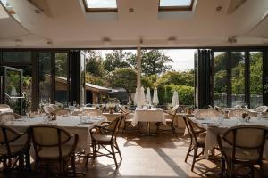 a restaurant with white tables and chairs and windows at The Georgian House in Alderney