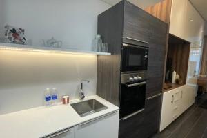 uma cozinha com um lavatório e um micro-ondas preto em Cloud9 Waterfront Luxury Condo em Manama
