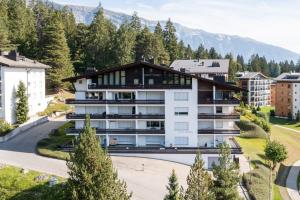 ein Apartmenthaus in einer Stadt mit Bergen im Hintergrund in der Unterkunft LAAX Homes - Casa Gronda 2 in Laax