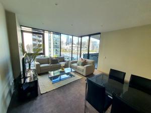 uma sala de estar com sofás, uma mesa e cadeiras em Harbour Escape Apartments Docklands em Melbourne