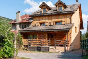 une grande maison en bois avec un toit en gambrel dans l'établissement La Gravière, à La Salle Les Alpes