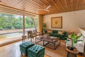 a living room with green furniture and a large window at LohonoStays Villa Athini in Chinchavli