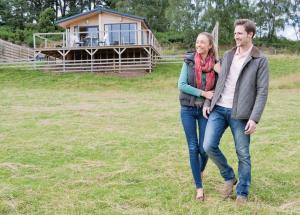 a man and woman walking in a field with a house in the background at Kessock Highland Lodges in North Kessock