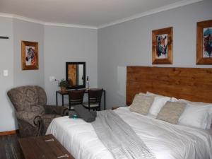 um quarto com uma grande cama branca e uma cadeira em Blesbok Inn em Polokwane
