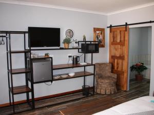 uma sala de estar com uma televisão de ecrã plano e prateleiras em Blesbok Inn em Polokwane