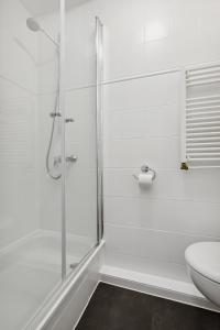 uma casa de banho branca com um chuveiro e um WC. em E&K Apartment Kahrstraße em Essen