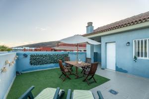 a patio with a table and chairs and an umbrella at San Borondón Sunset Apartment in Puertito de Güímar