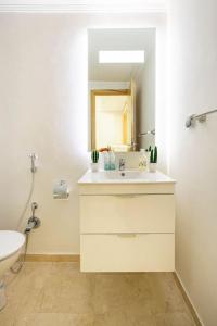 a white bathroom with a sink and a mirror at TT Holidays Cosy Apartment Hassan in Rabat