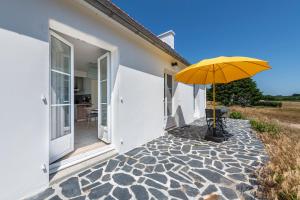 a yellow umbrella sitting on a patio next to a house at Beach House 1km de la plage in Audierne