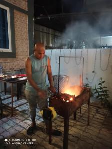 Ein Mann steht vor einem Grill in der Unterkunft Hotel Namo Buddha in Sauraha