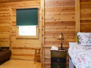 a bedroom with wooden walls and a window and a bed at Shimanologhouse - Vacation STAY 41662v in Iki