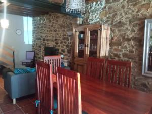 a dining room with a table and chairs and a stone wall at Casa típica asturiana en Ribota in Celleruelo