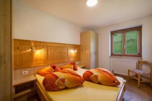 una camera con 2 letti con cuscini arancioni e gialli di Fichtenhof Wohnung Edelweiss a Tarces