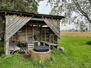 un antiguo edificio de madera en un campo con un árbol en Koskela en Kalajoki