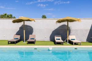 drie stoelen en parasols naast een zwembad bij WaterWheel Villa by Fidalsa in Almoradí