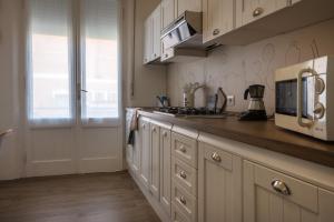 a kitchen with white cabinets and a microwave at Perla Marina Appartamento in Rimini +5 photos