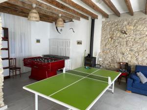una mesa de ping pong en una sala de estar con una pared de piedra. en Cal Tomaset en Las Cabanyas