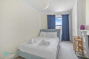 a bedroom with a bed with blue curtains and a window at 3 Bed - Admiralty Retreat by Pureserviced in Plymouth