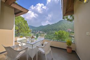 einen Balkon mit einem Tisch und Stühlen sowie Aussicht in der Unterkunft Jungle Lodge Resort in Kasauli