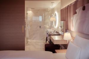 ein Hotelzimmer mit einem Bett und einem Bad mit einer Dusche in der Unterkunft Falkensteiner Balance Resort Stegersbach - Adults only in Stegersbach