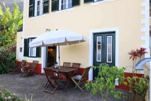 a table with an umbrella in front of a house at Quinta das Hortênsias in Arco de São Jorge