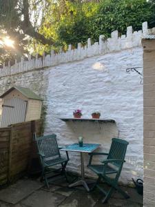 two chairs and a table in front of a wall at Cosy Cottage (Free parking) in Macclesfield