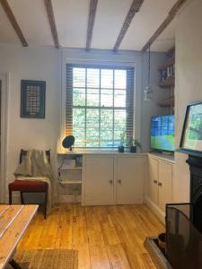 ein Wohnzimmer mit einem Schreibtisch und einem Fenster in der Unterkunft Cosy Cottage (Free parking) in Macclesfield