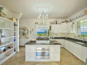 a kitchen with white cabinets and a chandelier at Larimar - Luxury Ocean Front Villa in Saint Philip